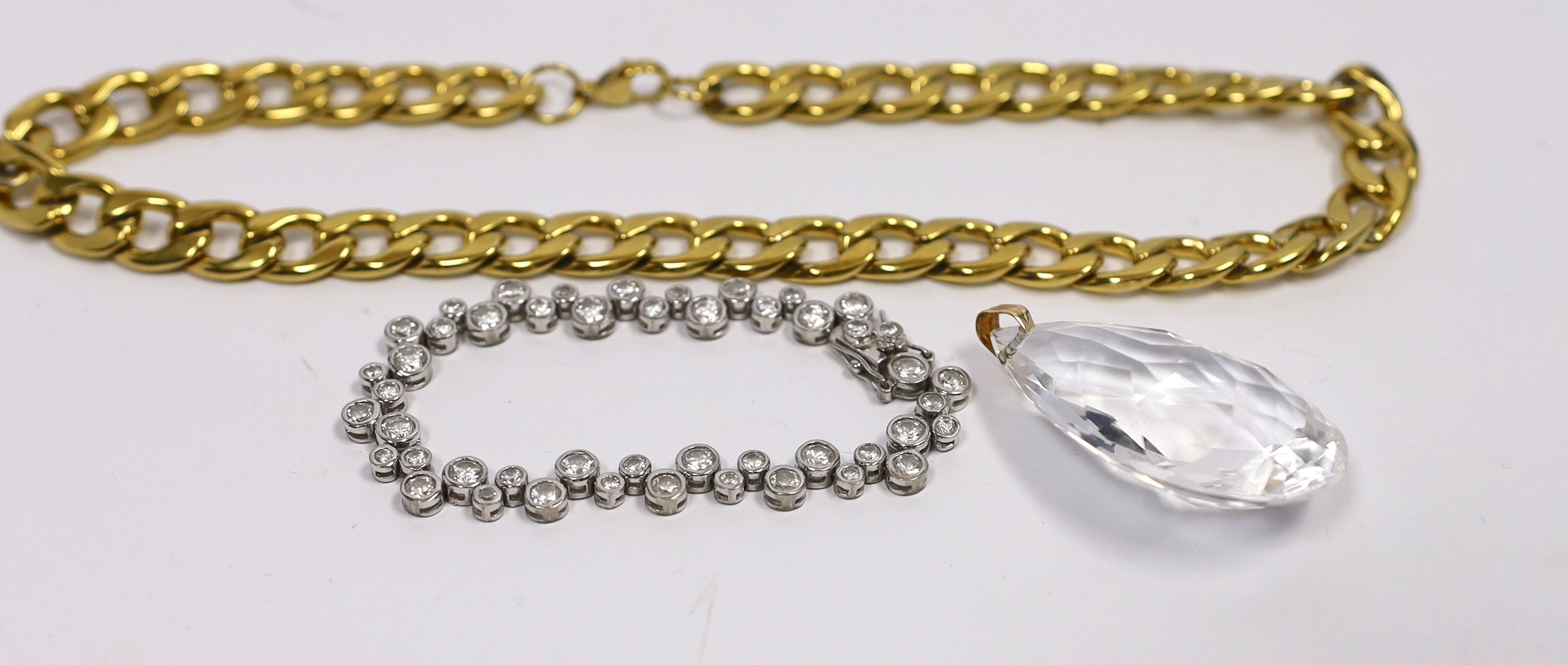A gilt metal curblink necklace, a white metal paste set bracelet stamped 925 and a rock crystal pendant with gilt metal loop